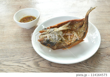 deep fried black-banded trevally fish on plate dipping spicy chili sauce deep fried black-banded trevally fish on plate dipping spicy chili sauce 114164573