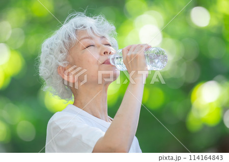 新緑の公園で水を飲むシニア女性 新緑の公園で水を飲むシニア女性 114164843