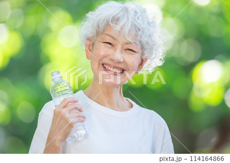 新緑の公園で水を飲むシニア女性 新緑の公園で水を飲むシニア女性 114164866