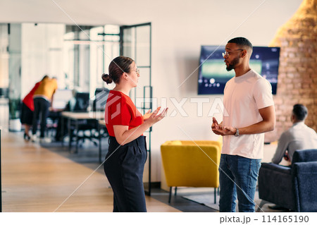 Young business colleagues, including an African American businessman, engage in a conversation about business issues in the hallway of a modern startup coworking center, exemplifying dynamic problem Young business colleagues, including an African American businessman, engage in a conversation about business issues in the hallway of a modern startup coworking center, exemplifying dynamic problem 114165190