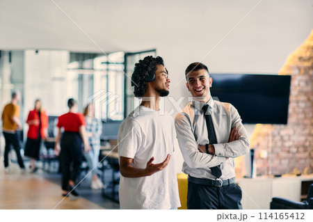 A group of colleagues, including an African American businessman and a young leader in a shirt and tie, pose together in a modern coworking center office, representing a dynamic blend of 114165412