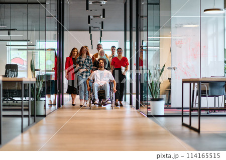 A diverse group of young business people walking a corridor in the glass-enclosed office of a modern startup, including a person in a wheelchair and a woman wearing a hijab A diverse group of young business people walking a corridor in the glass-enclosed office of a modern startup, including a person in a wheelchair and a woman wearing a hijab 114165515