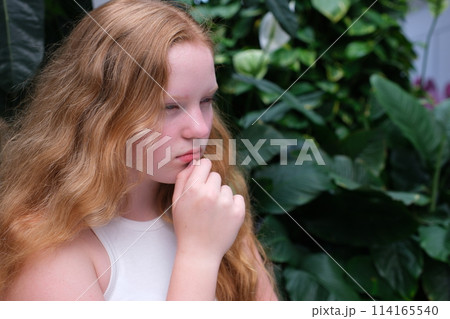 The girl, red-haired, put her hand to her chin, thinking, thinking, dreaming. High quality photo The girl, red-haired, put her hand to her chin, thinking, thinking, dreaming. High quality photo 114165540