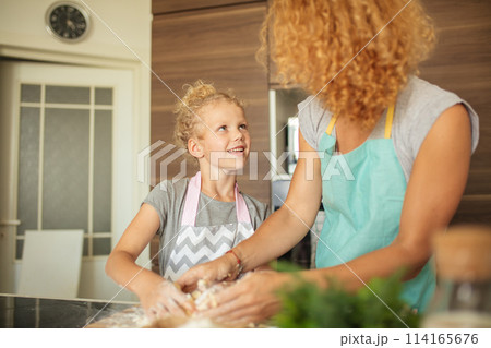 Woman and cute daughter cooking on kitchen, making dough for birthday party. 114165676