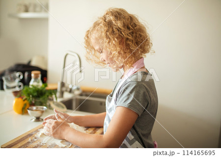 Woman and cute daughter cooking on kitchen, making dough for birthday party. 114165695