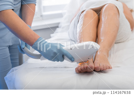 A woman is undergoing a photoepilation procedure in a beauty salon, trusting laser hair removal to a cosmetologist. An expert in cosmetology performs the procedure of laser hair removal on the client 114167638