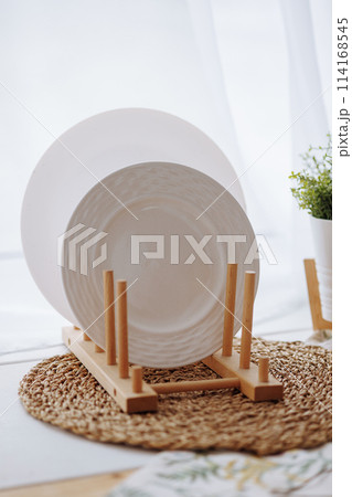A white plate is on a wooden stand next to a potted plant A white plate is on a wooden stand next to a potted plant 114168545