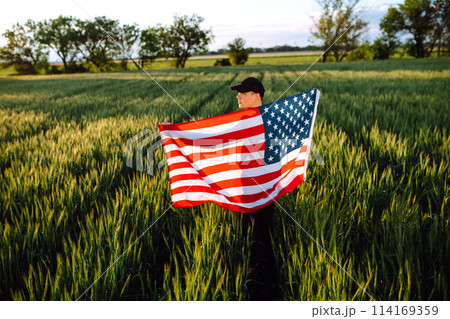 Man hold waving american USA flag. Patriot raise national american flag. Independence Day, 4th July. Man hold waving american USA flag. Patriot raise national american flag. Independence Day, 4th July. 114169359