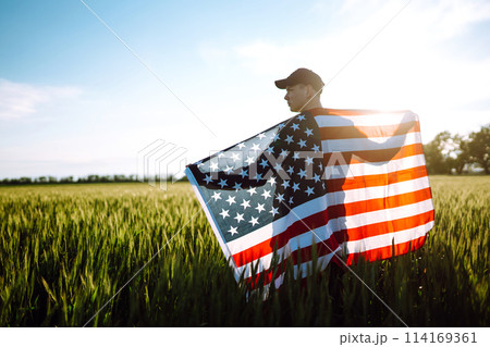 Man hold waving american USA flag. Patriot raise national american flag. Independence Day, 4th July. 114169361