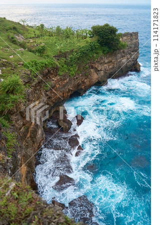 Cinematic aerial landscape shots of the beautiful island of Nusa Penida. Huge cliffs by the shoreline and hidden dream beaches with clear water and foaming wave. 114171823