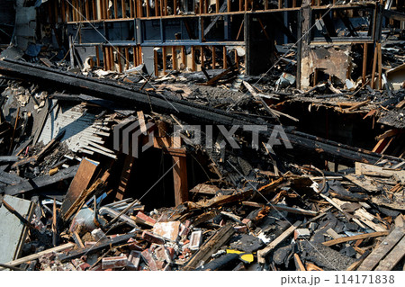 A burnt-out old wooden building after a fire. Charred beams after the destruction 114171838