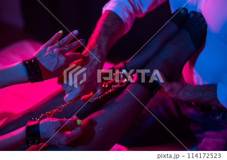 A man holds a woman by the ankles. BDSM concept. A man holds a woman by the ankles. BDSM concept. 114172523