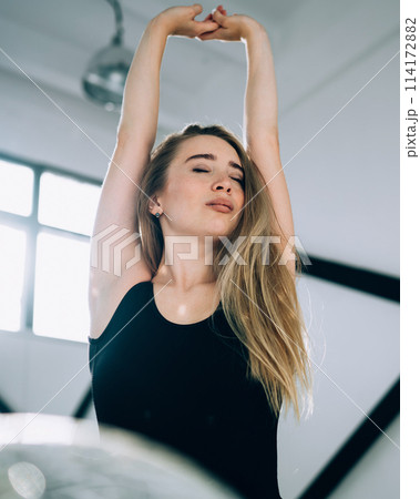 Slim female with closed eyes putting hands up 114172882