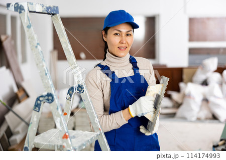 Portrait of female house painter with tools in renovated room Portrait of female house painter with tools in renovated room 114174993
