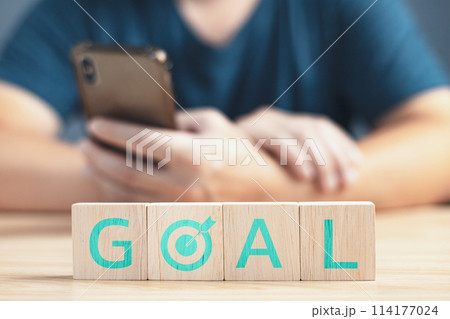 a businessman sit on table the wooden block on the goal to business finance and strategy. 114177024