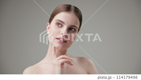 Beauty, health, cosmetics, anti-aging therapy and skin care concept - young beautiful brunette Caucasian woman touching face and looking at camera Beauty, health, cosmetics, anti-aging therapy and skin care concept - young beautiful brunette Caucasian woman touching face and looking at camera 114179498