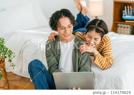 くつろぎながらパソコンを見るカップル 114179829