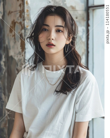 Asian woman in oversized white t-shirt against the backdrop of a vintage cement wall in an old apartment. Asian woman in oversized white t-shirt against the backdrop of a vintage cement wall in an old apartment. 114180551
