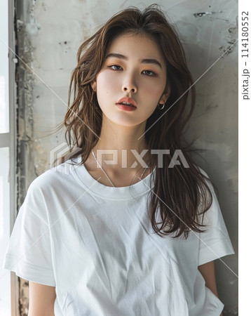 Asian woman in oversized white t-shirt against the backdrop of a vintage cement wall in an old apartment. Asian woman in oversized white t-shirt against the backdrop of a vintage cement wall in an old apartment. 114180552