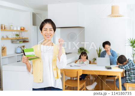 ダイニングルームで通帳を持つ主婦 114180735