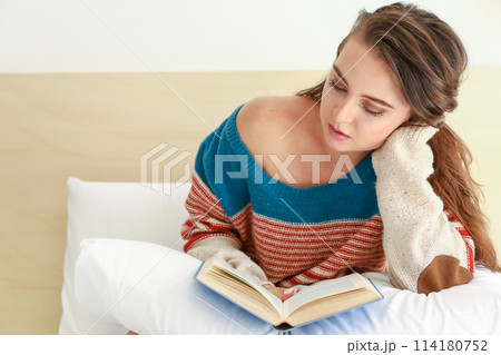 Teenager reads a book resting on her hand Teenager reads a book resting on her hand 114180752