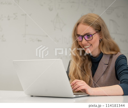 Caucasian woman scientist typing on laptop. White board with formulas. Caucasian woman scientist typing on laptop. White board with formulas. 114181344