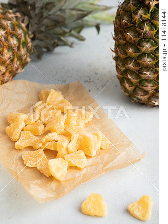 Yellow organic dried sweet pineapple slices on baking paper on light table.Macro 114181441
