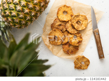 Organic sweet pineapple circle slices on in baking paper with knife on light table. Organic sweet pineapple circle slices on in baking paper with knife on light table. 114181442
