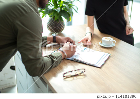 Two business people discuss meeting table with documents and write notes 114181890