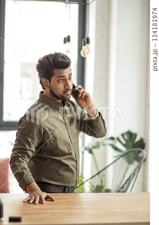 Indian business man talking on phone in modern office 114181974
