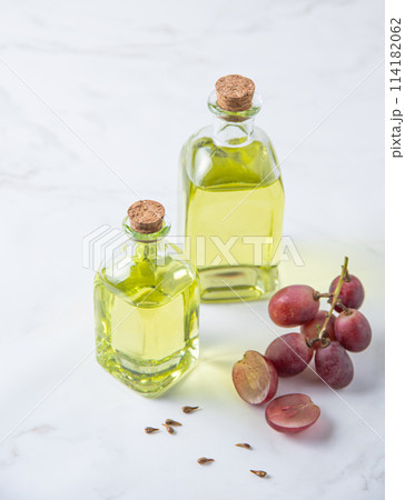 natural dietary and vegan grape seed oil in glass bottles on a white marble background. natural dietary and vegan grape seed oil in glass bottles on a white marble background. 114182062