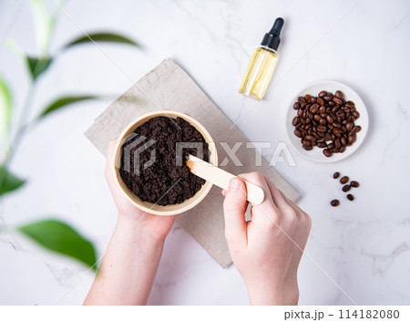 Home skin care. A young woman mix a homemade coffee scab with oil from recycled capsules Home skin care. A young woman mix a homemade coffee scab with oil from recycled capsules 114182080