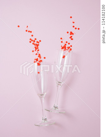 Flat lay of celebration. Two glasses with confetti on a pastel pink background. Flat lay of celebration. Two glasses with confetti on a pastel pink background. 114182100