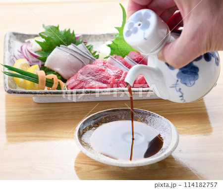 鯨のお刺身盛り合わせをバックにお醤油を注ぐ 鯨のお刺身盛り合わせをバックにお醤油を注ぐ 114182757