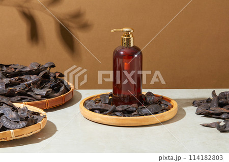 Empty label pump bottle placed on a wooden dish with black locust fruits around. Brown background with natural shadow. Natural beauty blank label for branding mock-up concept Empty label pump bottle placed on a wooden dish with black locust fruits around. Brown background with natural shadow. Natural beauty blank label for branding mock-up concept 114182803