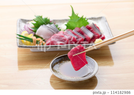 ミンク鯨の赤身と本皮のお刺身をお醤油につける 114182986