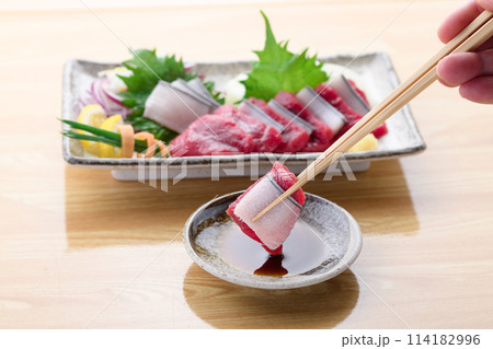 ミンク鯨の赤身と本皮のお刺身をお醤油につける 114182996