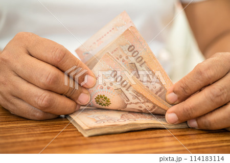 Asian business woman holding Thai banknote currency money. 114183114