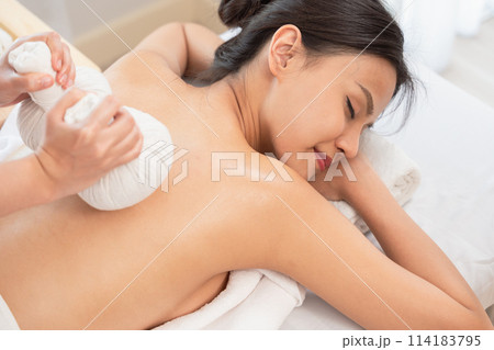 Beautiful young happy woman having back massage with herb pouches. 114183795