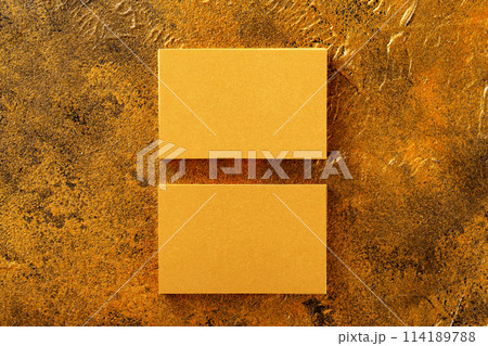 Flatlay mockup of two horizontal golden foil business cards at golden textured luxury background. 114189788