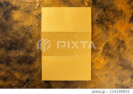 Top view mockup of opened three fold golden foil brochure isolated at golden textured background. 114189852