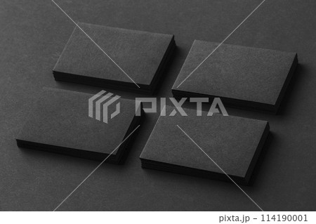 Mockup of four black business cards stacks arranged in rows at black paper background. 114190001