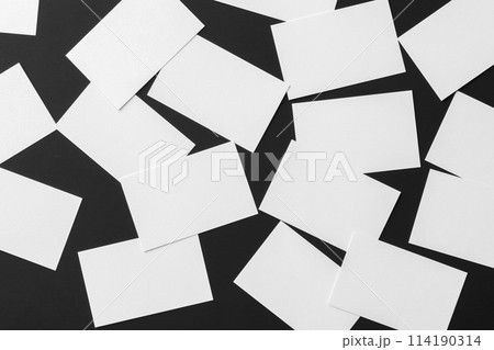 Top view mockup of white horizontal business cards scattered at black textured paper background. Top view mockup of white horizontal business cards scattered at black textured paper background. 114190314