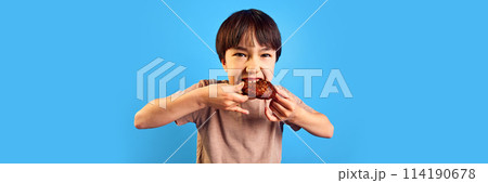 Little boy, child emotionally biting fried meat, cutlet from burger against blue background 114190678