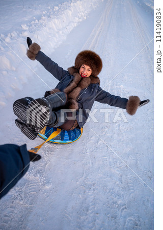 a beautiful girl in a fur jacket and hat walks and has fun in the winter forest. 114190834