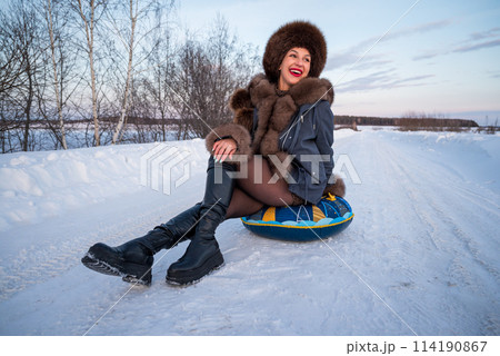 a beautiful girl in a fur jacket and hat walks and has fun in the winter forest. 114190867