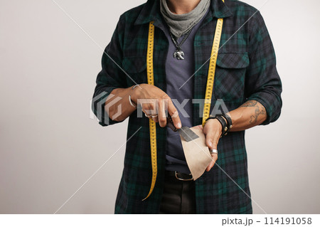 Cropped image of a shoemaker with measure tape and tools 114191058