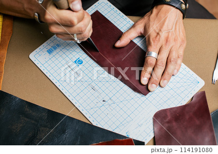 Close up of skinner craftsman working with natural leather using craft tools. Close up of skinner craftsman working with natural leather using craft tools. 114191080