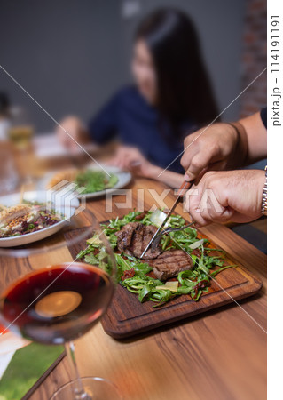 man in the cafe eats beef steak with greens close-up man in the cafe eats beef steak with greens close-up 114191191