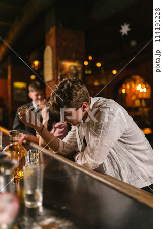 Sad man in wrinkled shirt drinks hard alcohol in bar Sad man in wrinkled shirt drinks hard alcohol in bar 114191228